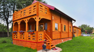 Foto van Domek letniskowy PATRYK Ostrowiec Slawienski, een houten lodge met bloemen op het grasveld.