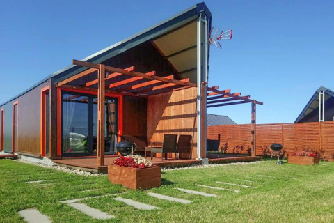 Moderne feriebolig ved Domki wakacyjne Jezierzany i Danmark, med terrasse, grøn græsplæne og solrig himmel.
