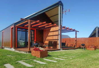 Cabaña vacacional moderna en Domki wakacyjne Jezierzany, Dinamarca, con terraza, césped y cielo despejado.