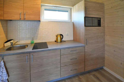Moderne houten keuken met spoelbak, kookplaat, waterkoker en microgolfoven in Sarbinowo, Denemarken.