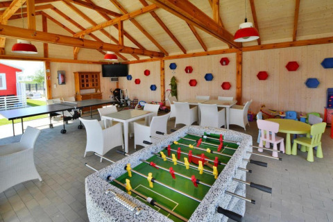 Speelruimte in lodge met tafelvoetbal, pingpongtafel, zitplekken en kleurrijke kinderspeelhoek.
