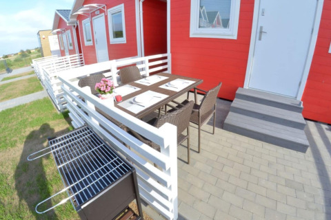 Buitenterras met tafel, stoelen en barbecue voor rode vakantiewoningen in Sarbinowo, Denemarken.