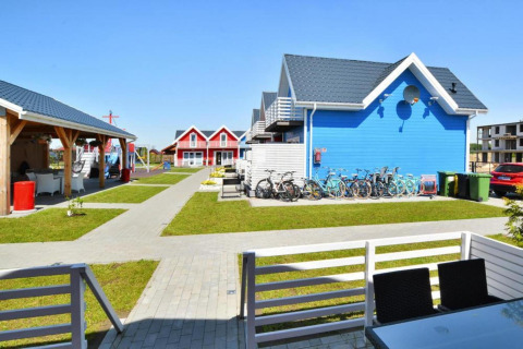 Kleurrijke vakantiewoningen in Sarbinowo, Denemarken, met fietsen, terras en speeltuin in de buurt.