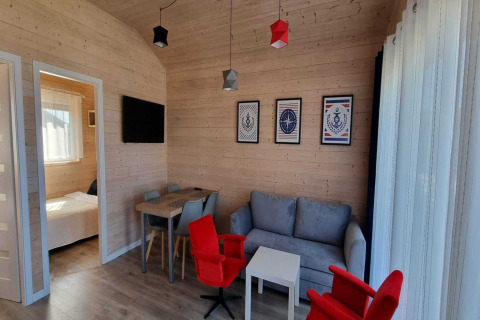 Moderne vakantiewoning in Sarbinowo met houten wanden, comfortabele zithoek en slaapkamer zichtbaar.
