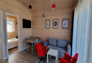 Moderne vakantiewoning in Sarbinowo met houten wanden, comfortabele zithoek en slaapkamer zichtbaar.