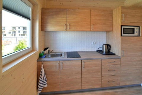 Moderne kitchenette met houten kasten, spoelbak, kookplaat en waterkoker in een Sarbinowo lodge.
