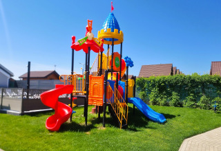 Colorido parque infantil con toboganes y torre en césped en Single-storey holiday cottages Sarbinowo.