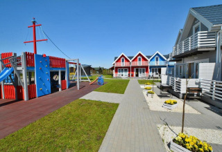 Kleurrijke vakantiehuisjes en speeltuin bij zonnig weer in Single-storey holiday cottages Sarbinowo.