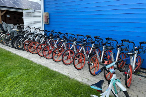 Eine Reihe Fahrräder mit orangefarbenen Rädern vor einer blauen Wand bei Single-storey holiday cottages Sarbinowo.