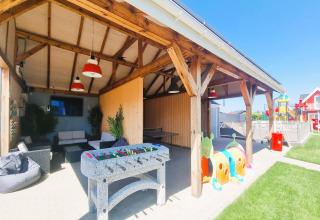 Überdachter Sitzbereich bei Single-storey holiday cottages Sarbinowo mit Kicker, Couch und Spielplatz.
