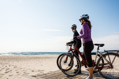 Twee fietsers met helm genieten van het strand bij Single-storey holiday cottages Sarbinowo, Denemarken.