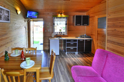 Interieur van een gelijkvloerse chalet in Ustronie Morskie met houten muren, keuken en roze zetel.