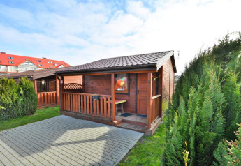 Chalet en bois de plain-pied de 30 m2 avec terrasse et arbustes, situé à Ustronie Morskie, Danemark.