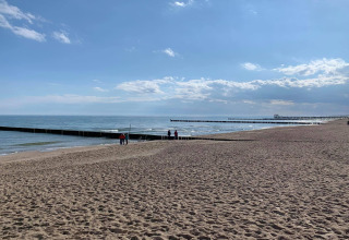 Strandzicht vanuit een huisje in Ustronie Morskie, Denemarken, met zee, pieren en zand.