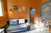 Sala de estar con paredes de madera, sofá gris, mesa de comedor y cuatro sillas en Older year-round cottage TYPE A Ustronie Morskie, Dinamarca.