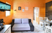 Sala luminosa de Older Cottage TYPE A Ustronie Morskie con paredes de madera, sofá, TV y comedor.