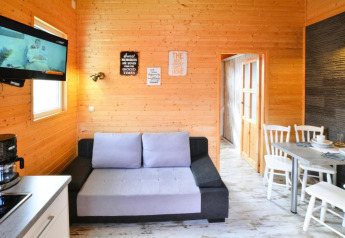 Lichte leefruimte in Older Cottage TYPE A Ustronie Morskie met houten wanden, sofa, tv en eetruimte.