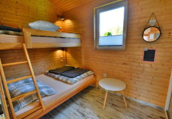 Kamer in Older jaarrond cottage TYPE A Ustronie Morskie met stapelbed, raam en tafel, Denemarken.