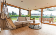 Modernes Wohnzimmer einer Lodge mit Hängesessel, Sofa, und Panoramablick auf Garten in Slowenien.