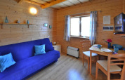 Accogliente soggiorno in legno con divano blu, tavolo da pranzo e finestra, Holiday cottages Sarbinowo, Danimarca.