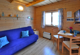 Accogliente soggiorno in legno con divano blu, tavolo da pranzo e finestra, Holiday cottages Sarbinowo, Danimarca.