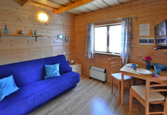 Accogliente soggiorno in legno con divano blu, tavolo da pranzo e finestra, Holiday cottages Sarbinowo, Danimarca.