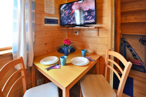 Knusse eethoek in houten huisje met tafel voor twee en tv aan de muur, Holiday cottages Sarbinowo, Denemarken.
