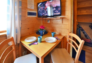 Knusse eethoek in houten huisje met tafel voor twee en tv aan de muur, Holiday cottages Sarbinowo, Denemarken.