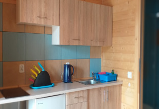 Piccola cucina in una baita di Holiday cottages Sarbinowo, Danimarca, con armadietti e coltelli colorati.