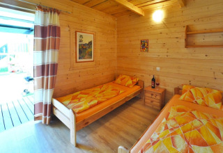 Houten hut slaapkamer met twee eenpersoonsbedden en kleurrig beddengoed bij Holiday cottages Sarbinowo.