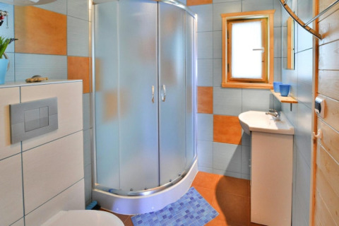 Baño moderno en casa de vacaciones con cabina de ducha, inodoro, lavabo y azulejos de colores.
