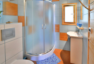 Moderne badkamer in vakantiehuisje met douchecabine, toilet, wastafel en gekleurde wandtegels.