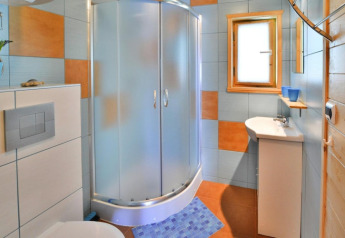 Modern bathroom in holiday cottage with shower cabin, toilet, small washbasin and colorful tiles.