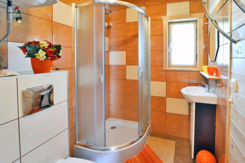 Modern bathroom at Holiday cottages Sarbinowo, Denmark, with shower cabin, orange tiles, and window.
