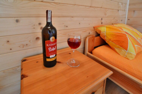 Una bottiglia di vino Kadaritsa Soleil e un bicchiere su un tavolino in una cabina accogliente alle Holiday cottages Sarbinowo.