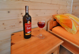 Een fles Kadaritsa Soleil wijn en een glas op een houten tafel in een gezellige hut bij Holiday cottages Sarbinowo.