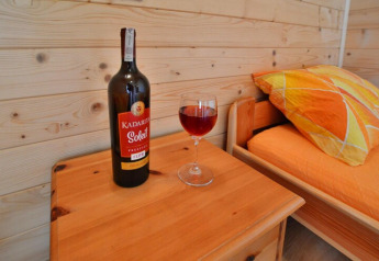 Una bottiglia di vino Kadaritsa Soleil e un bicchiere su un tavolino in una cabina accogliente alle Holiday cottages Sarbinowo.
