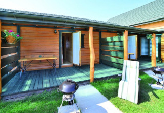 Terrazza esterna alle case vacanza a Sarbinowo, Danimarca, con barbecue, panca e prato verde.