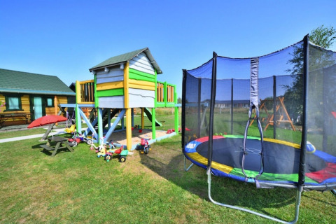 Area giochi colorata con casetta, tappeto elastico e giocattoli presso Holiday cottages Sarbinowo, Danimarca.