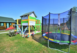 Speeltuin met houten huisje, kleurrijke trampoline en speelgoed bij Holiday cottages Sarbinowo in Denemarken.