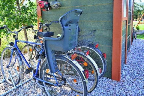 Biciclette con seggiolino bimbo e cestino parcheggiate presso una baita verde a Holiday cottages Sarbinowo.