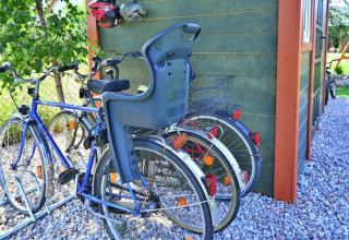 Fietsen met kinderzitje en mand bij een groen huisje op kiezels in Holiday cottages Sarbinowo, Denemarken.