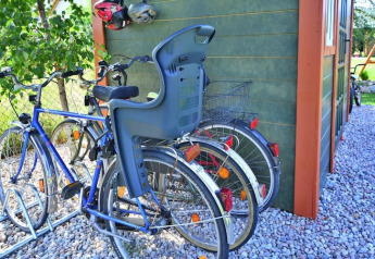 Bicicletas con asiento infantil y cesta aparcadas junto a una cabaña verde en Holiday cottages Sarbinowo.
