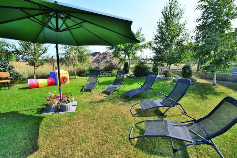 Buiten ontspanningsplek bij Holiday cottages Sarbinowo, Denemarken, met ligstoelen, parasol en kinderspeelgoed.