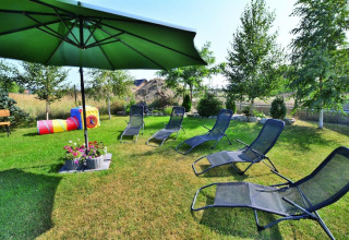 Area relax all'aperto presso Holiday cottages Sarbinowo, Danimarca, con lettini, ombrellone e giochi per bambini.