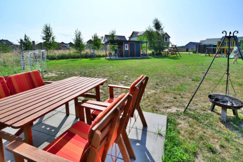Tuin met houten tuinset, speeltuin, vuurschaal en grasveld bij Holiday cottages Sarbinowo, Denemarken.