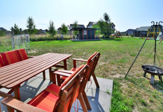 Tuin met houten zitmeubilair, speeltuin en vuurkorf bij Holiday cottages Sarbinowo in Denemarken.