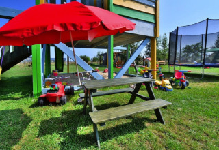 Área de juegos en Holiday cottages Sarbinowo, Dinamarca, con juguetes, mesa y sombrilla roja en el césped.
