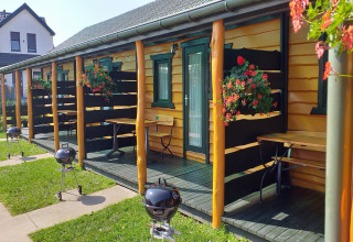 Vakantiehuisjes in Sarbinowo met privéterrassen, bloemen en barbecues op een zonnige dag in Denemarken.