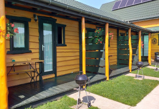 Vakantiechalets in Sarbinowo met gele wanden, groene deuren, veranda’s, barbecues en bloemen.